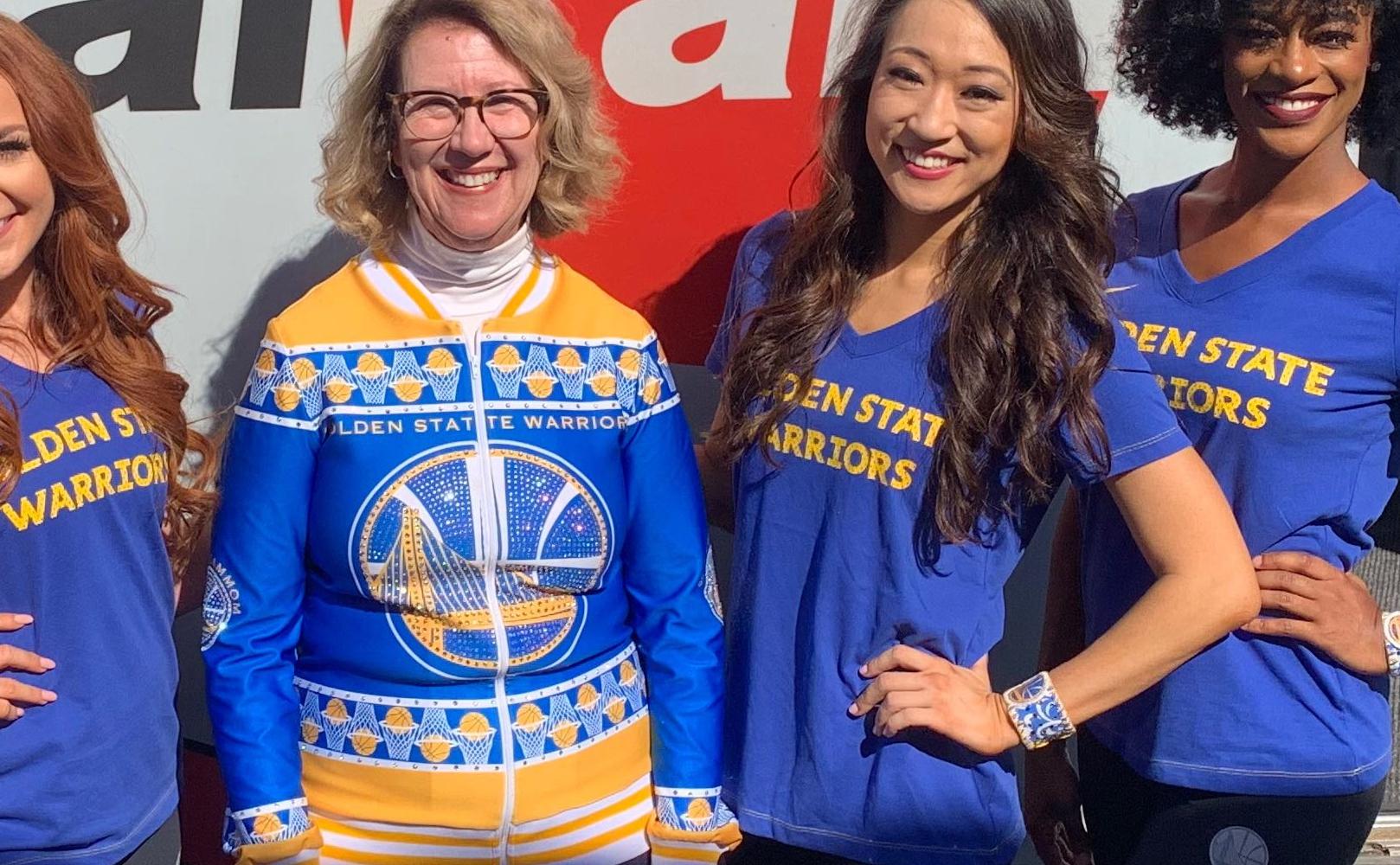 The Warriors Dance Mom and the Warriors Dance Team stand before a Caltrain train, looking fabulous