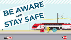 Adorable cartoon monsters surround an electric train, encouraging people to "Be Aware and Stay Safe"