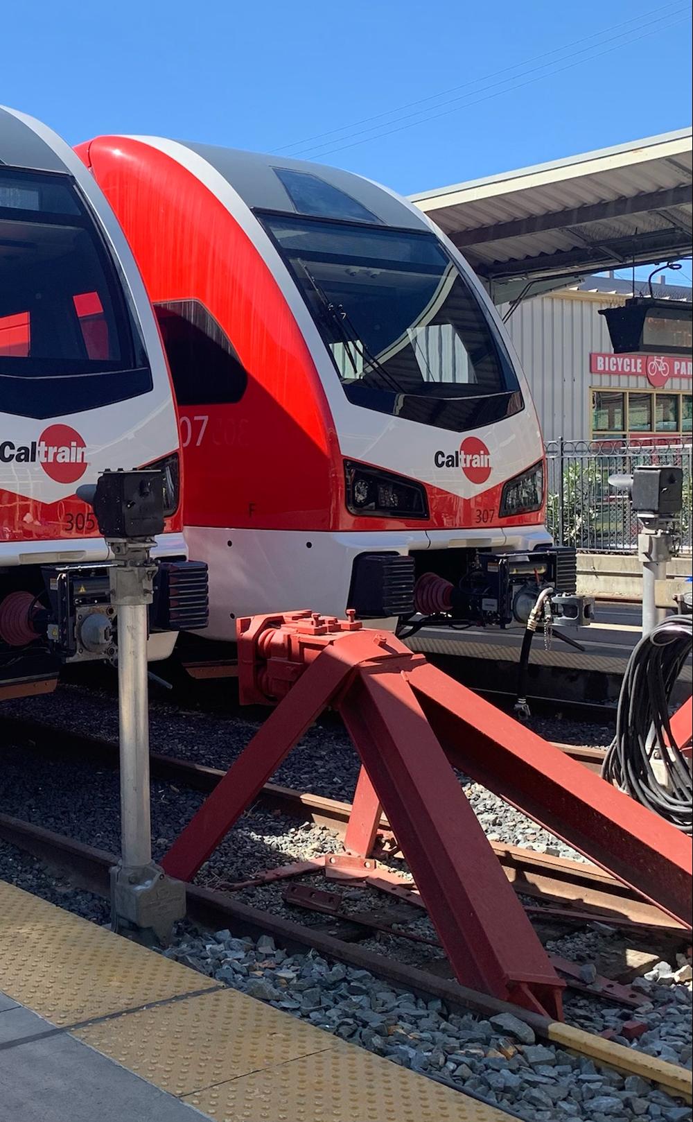 Two electric trains sit side by side at the San Francisco Station.