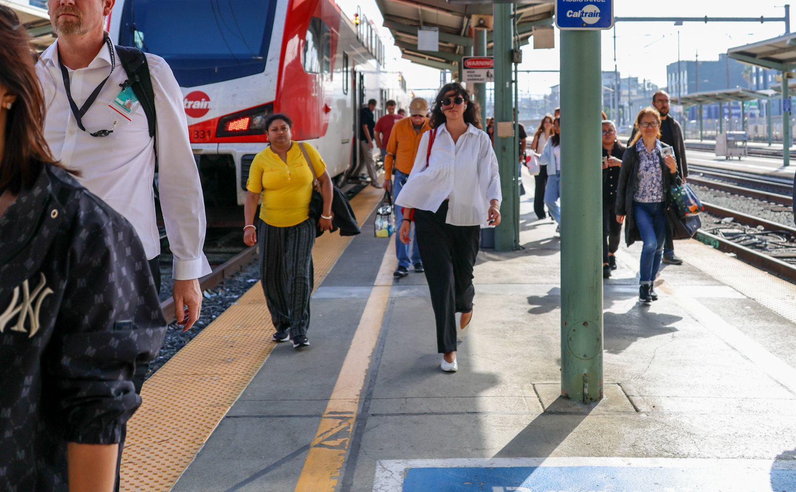 Riders depart from Caltrain at San Francisco Station while one looks particularly fabulous