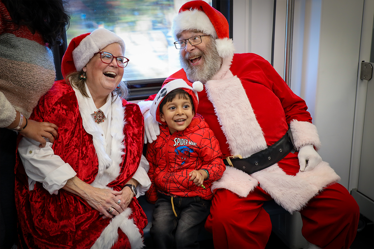 Santa and Mrs. Claus posing with smiling kid