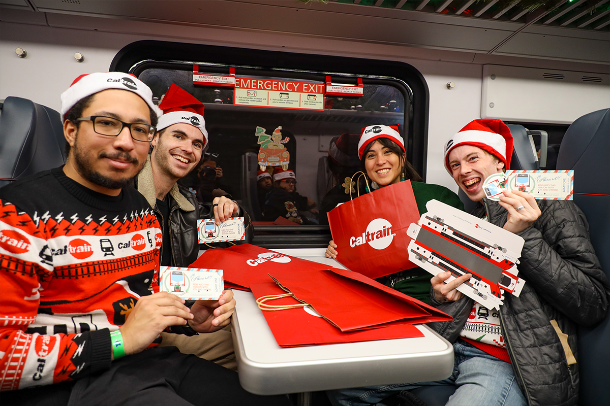 Group in holiday sweaters posing in train