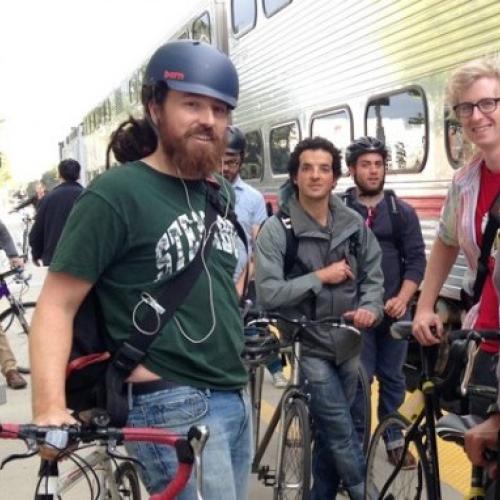 Many bikers congregate outside on a Caltrain platform. Bikers as in people with bicycles, not the Sons of Anarchy kind of bikers.