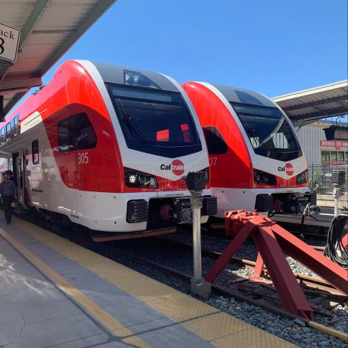 Two electric trains sit side by side at the San Francisco Station.