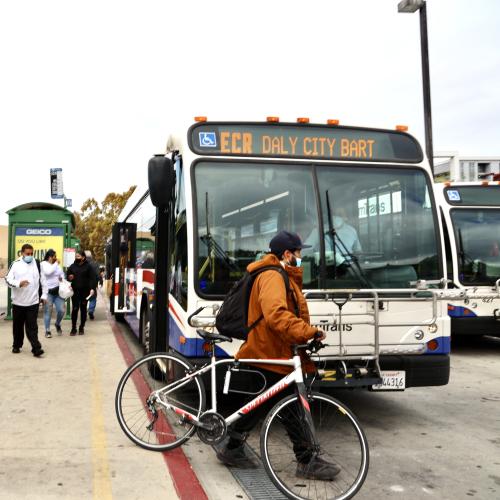 Person with a bike passing in front of a bus.