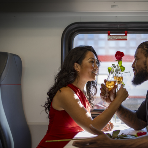 Couple clinking glasses in Caltrain cabin