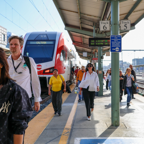 Riders depart from Caltrain at San Francisco Station while one looks particularly fabulous