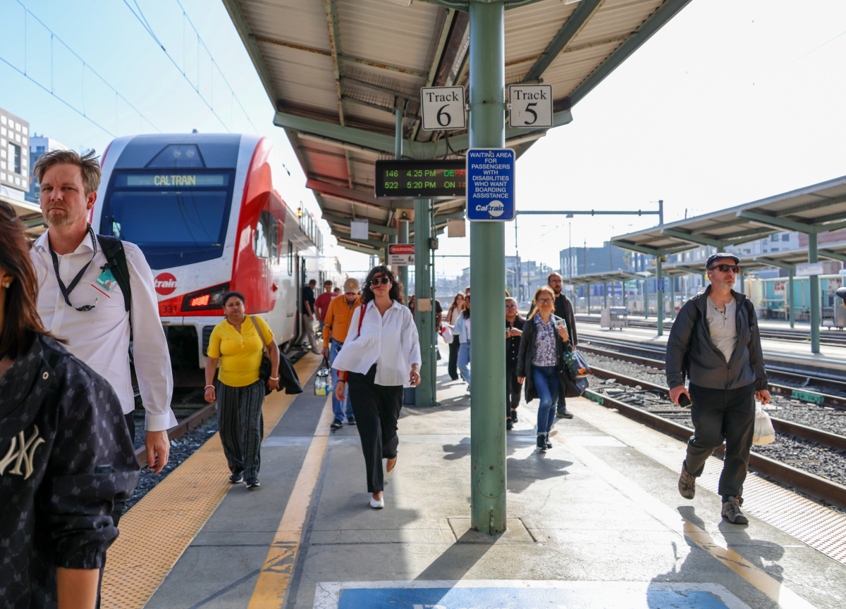 Riders depart from Caltrain at San Francisco Station while one looks particularly fabulous